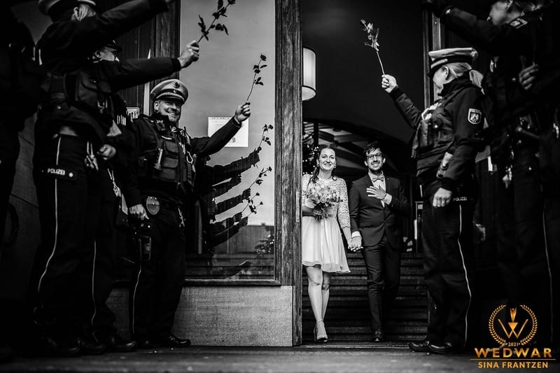 Hochzeitspaar wird von den Arbeitskolleg*innen der Polizei vorm Standesamt mit Rosen empfangen. - Gewinnerbild Wedwar Awards - Hochzeitsfotografin Sina Frantzen bildsprache Remscheid