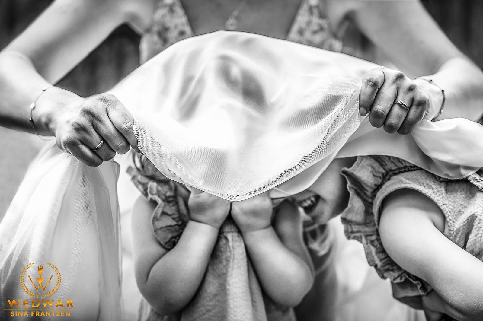Kinder verstecken sich unterm Brautkleid bei der Hochzeit im Eierkaal Remscheid. Hochzeitsfotograf Remscheid. Hochzeitsfotografin Sina Frantzen bildsprache. Gewinnerbild Wedwar Awards