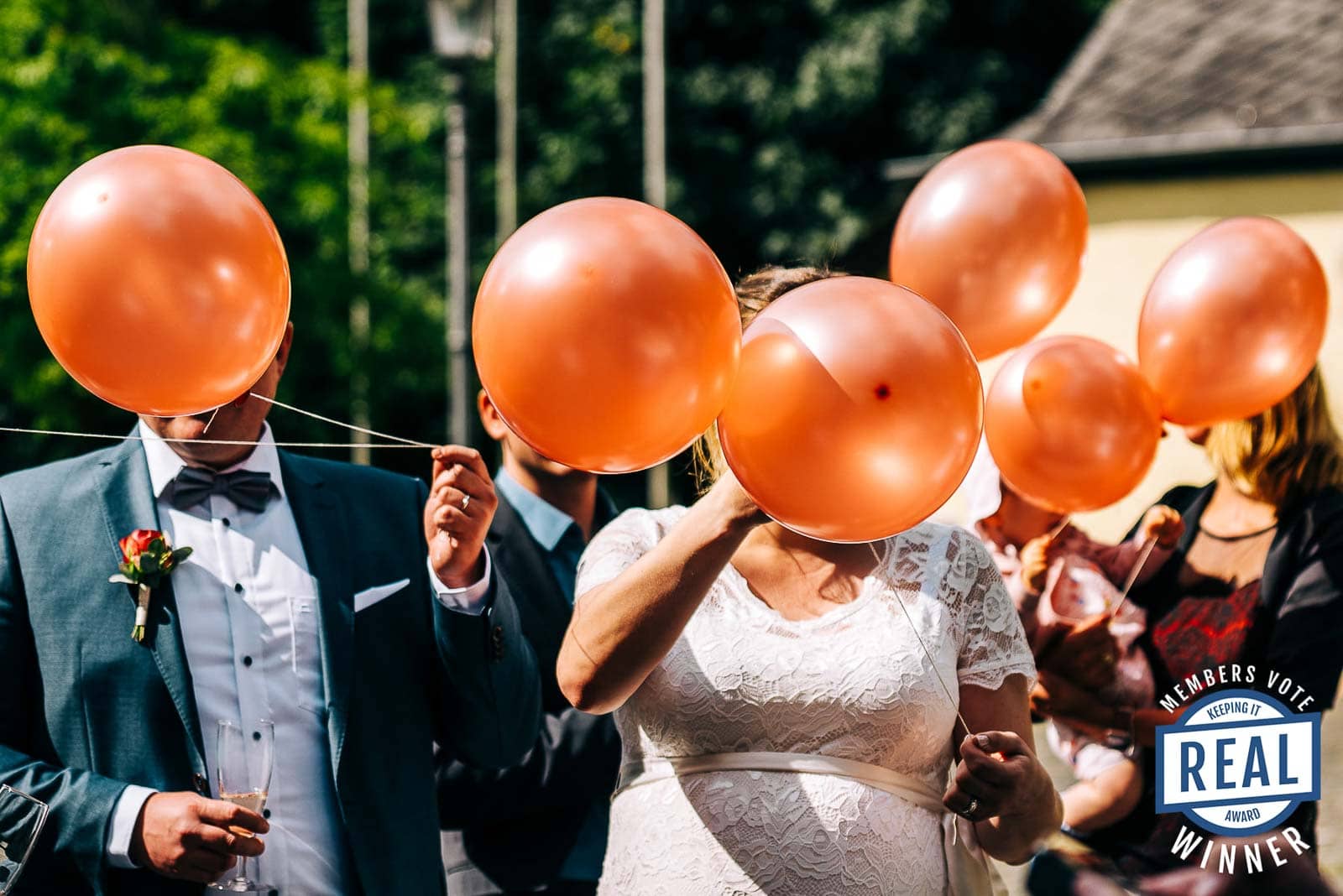 Ballons vor den Gesichtern einer Hochzeitsgesellschaft - Gewinnerbild Photograhers Keeping it Real Award